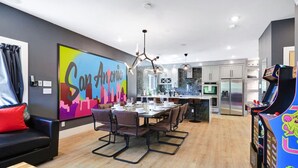 A modern living space with a dining area, kitchen, and arcade games. - City Views Rooftop Karaoke, Pool, Hot Tub, Games (San Antonio)