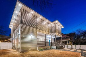 Ein modernes, zweistöckiges Haus mit überdachter Veranda und sichtbarer Garage.