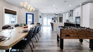 A modern kitchen with a dining area, a foosball table, and a large window. - Stylish 6BR/5BA, DT, Hot Tub, Games, Sleeps 20+ (San Antonio)