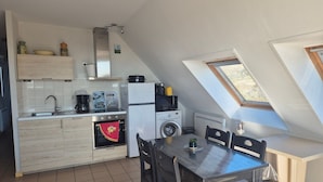 A compact kitchen with a dining area, a washing machine, and a small window. - Apartment sea view - 4 guests (Fort-Mahon-Plage)