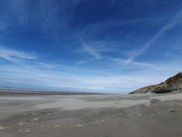 A beach with a wide sandy area and a clear sky.