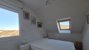 A bedroom with a single bed, a small bedside table, a nightstand, a window, and a skylight. - Apartment sea view - 4 guests (Fort-Mahon-Plage)