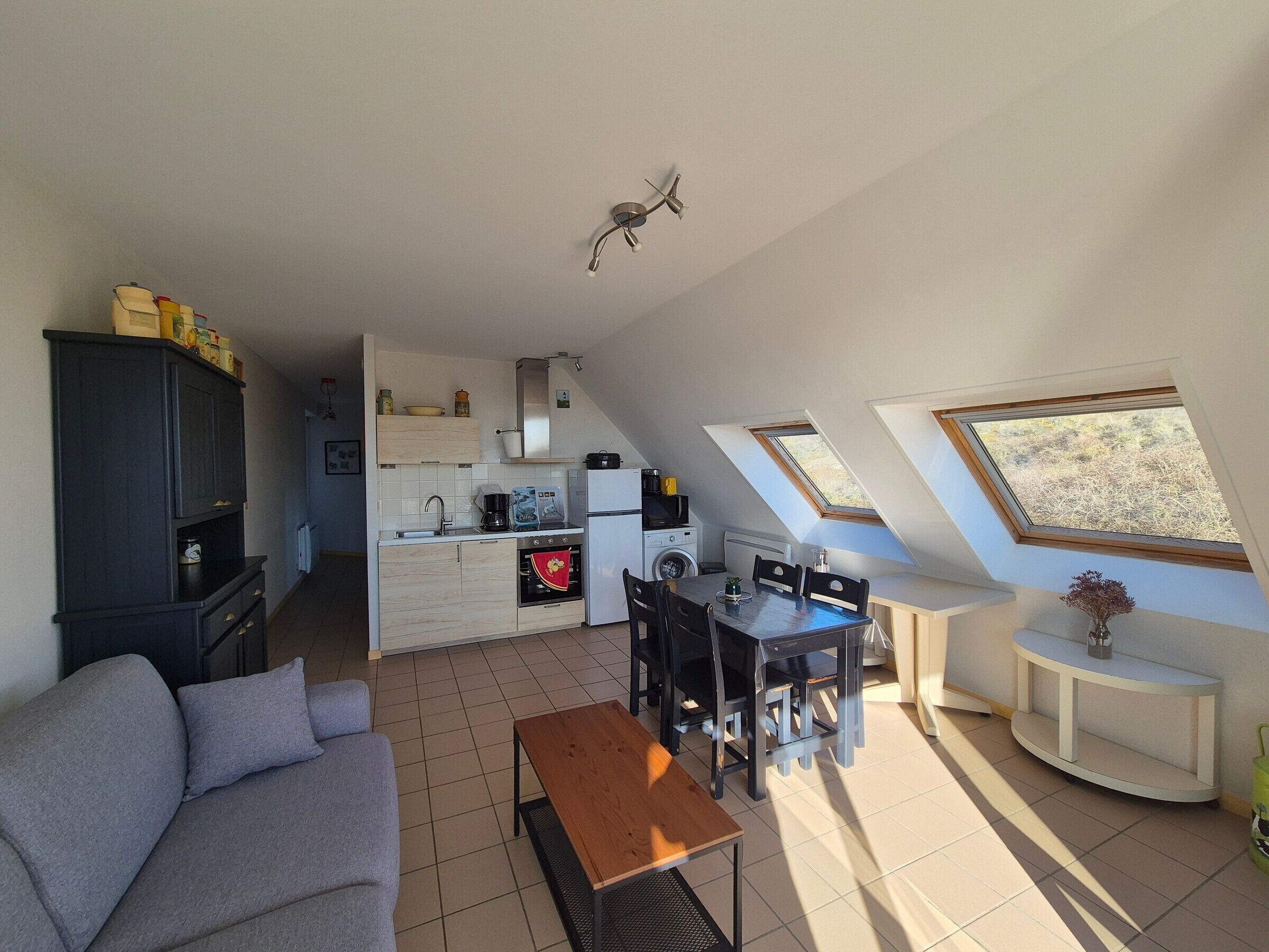 Een knus woongedeelte met een kitchenette, een eethoek en een bank.