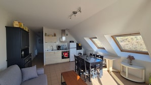 A compact living space with a kitchenette, a dining area, and a sofa. - Apartment sea view - 4 guests (Fort-Mahon-Plage)