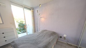 Ein Schlafzimmer mit einem Bett, einem Schminktisch, einem Fenster mit Vorhängen und einer Wandlampe.