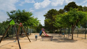 Un'area giochi con altalene, uno scivolo e panchine.