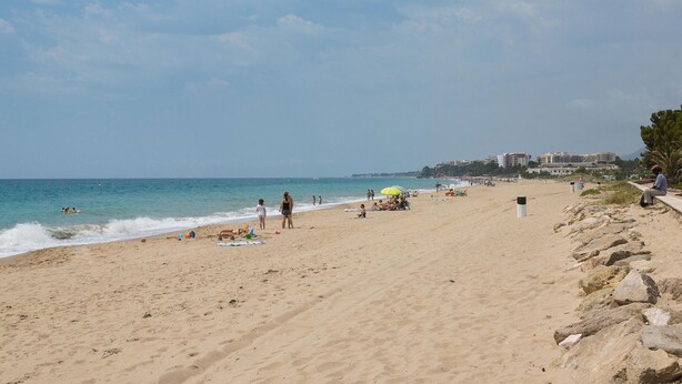 Una spiaggia con persone, ombrelloni e edifici sullo sfondo.