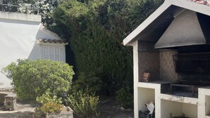 Un patio in pietra con una griglia barbecue e un piccolo giardino.