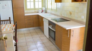 Una cucina con mobili in legno, un piano di lavoro bianco, una finestra e una macchina da caffè.