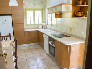 A kitchen with wooden cabinets, a white countertop, a window, and a coffee maker. - Family Villa for 6 with Air Conditioning and Parking (Mont-roig del Camp)