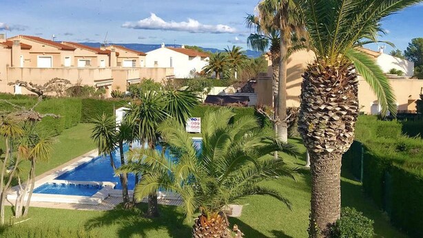 A pool surrounded by palm trees and a building with a tiled roof. - Charming Family House Near Beach with Pool (Miami Playa)