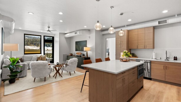 Una cocina moderna con una isla central, armarios de madera e iluminación colgante.