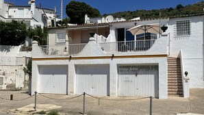 Un edificio bianco con tre porte per garage, un piccolo balcone e una scala che conduce al piano superiore.