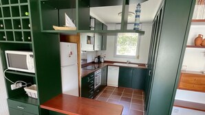 Una cucina compatta con forno a microonde, frigorifero, lavello e un piccolo angolo ristoro.