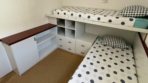 Una stanza in dormitorio con due letti a castello, una scrivania in legno e cassettiere integrate.