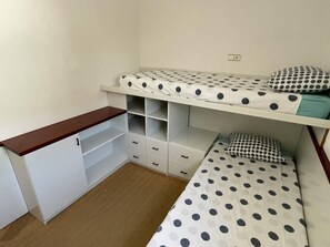 A dormitory room with two bunk beds, a wooden desk, and built-in storage drawers. - Charming Seaside House in Roses near Almadraba Beach, Sleeps 4 (Roses)