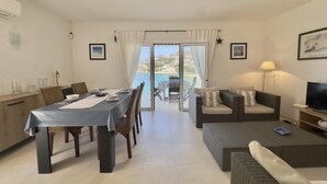 Un coin repas avec une table et des chaises, un canapé, un téléviseur et un balcon avec vue.