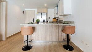 Eine moderne Küche mit Kochinsel, zwei Barhocker und einem eingebauten Backofen.