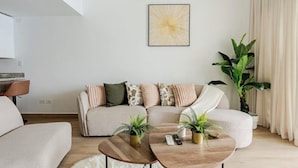Ein modernes Wohnzimmer mit einer Couch, zwei Couchtischen und einer großen Pflanze.