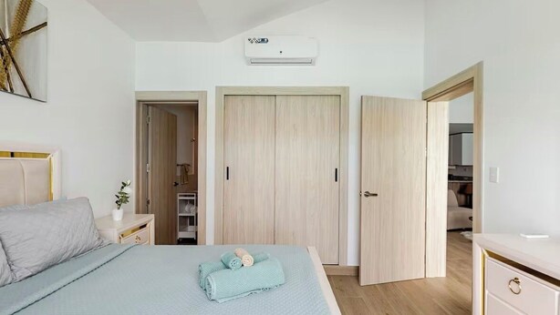 Ein Schlafzimmer mit Bett, Nachttisch, Wandgerät zur Klimatisierung und Kleiderschrank.