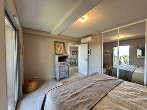 A bedroom with a bed, a wardrobe, a mirror, and a door leading to a balcony. - Sea view apartment, AC - 6 guests (Calvi)