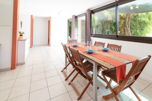 Zona pranzo con tavolo imbandito per quattro, sedie in legno e vista attraverso ampie finestre.