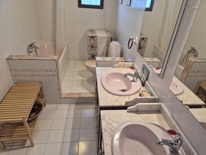 A bathroom with a wooden bench, two sinks, a bathtub, and a toilet. - Charming townhouse near river - 6 guests (Denia)