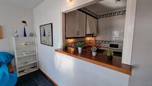 Een kleine keuken met een houten aanrecht, een magnetron en een betegelde spatwand.