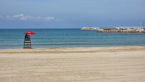 Een strand met een reddingstoren en een rotsenrij in de achtergrond.