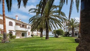 A well-maintained courtyard with palm trees, a swimming pool, and a building with multiple balconies. - Apartment with sea view - 4 guests (Denia)