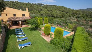 Una villa con piscina, tumbonas y un jardín bien cuidado.