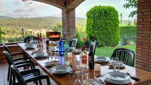 Una mesa de comedor para seis personas con sillas, una chimenea de ladrillo y vistas al campo.