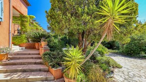 A stone staircase leading to a building with a garden featuring potted plants and a large tree. - Large villa for 2 families - 6 bedrooms - Secure swimming pool - Six-Fours (Six fours les plages)
