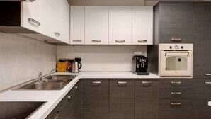 Een moderne keuken met een inbouwoven, een koffiezetapparaat en een waterkoker op het aanrecht.