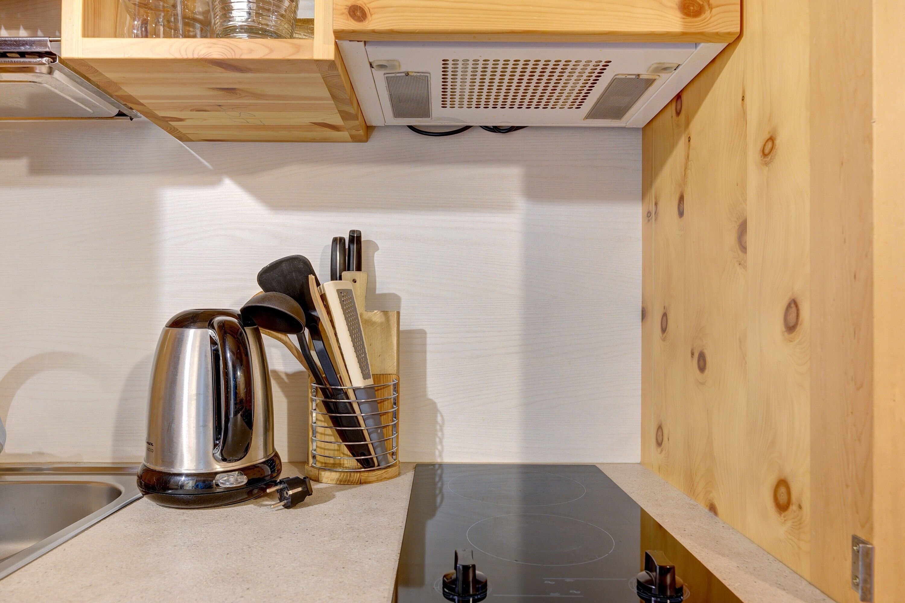 A kitchen with a kettle, knife block, and a built-in stove.
