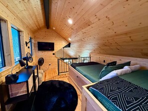 A cabin interior with a loft bed, a desk with a computer, and a window. - New Luxury Cabin/Hot Tub/Custom Playset/Firepit/Hammocks/Corn Hole/Games (Broken Bow)
