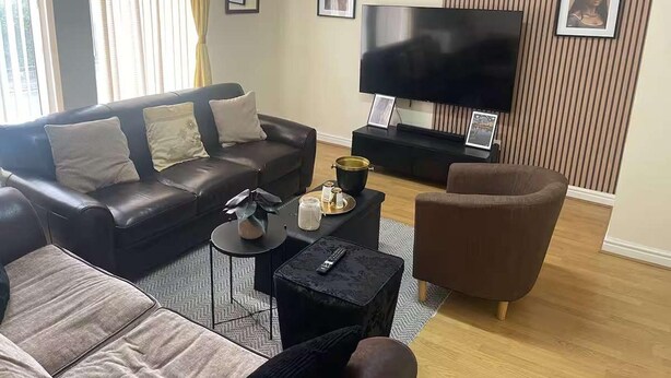 A modern living room with a leather sofa, a coffee table, a TV, and a brown armchair. - 1-bed Apt, Sleeps 4, Old Trafford Nearby (Manchester)