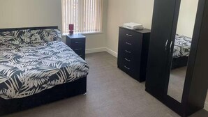 A bedroom with a bed, a dresser, a wardrobe, and a window with blinds. - 1-bed Apt, Sleeps 4, Old Trafford Nearby (Manchester)