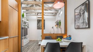Een moderne keuken met houten kastjes, een eettafel met zwarte stoelen en een hanglamp.