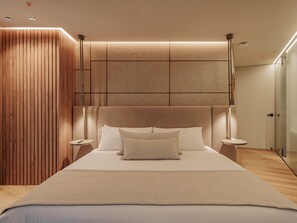 A modern bedroom with a large bed, wooden panel wall, and a glass door leading to a bathroom. - Devú (Medellín)