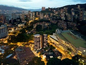 A cityscape at dusk with high-rise buildings, a central round building, and a large building with a green roof. - Devú (Medellín)