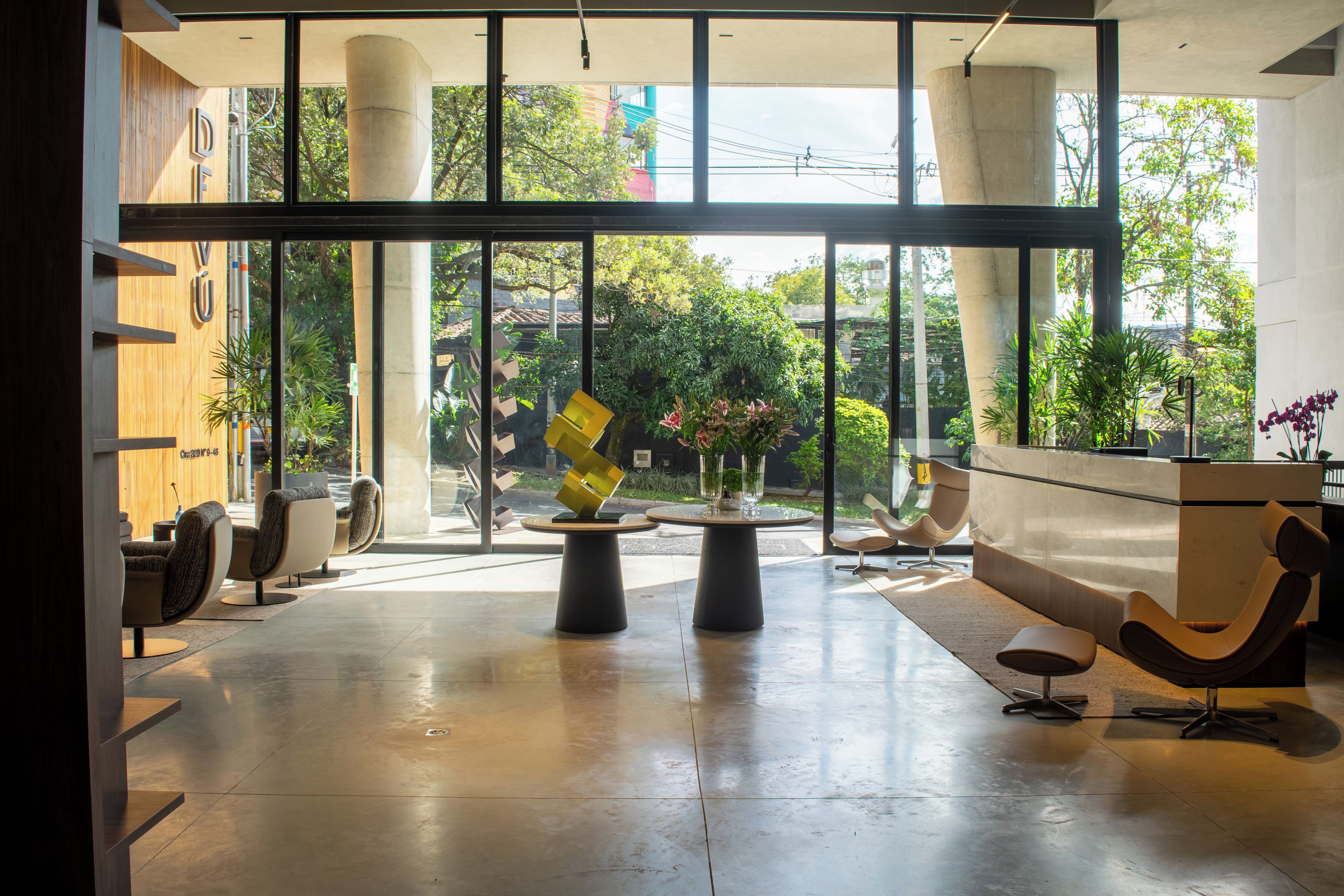 A spacious lobby with a reception desk, seating area, and large windows offering a view of the outdoors.