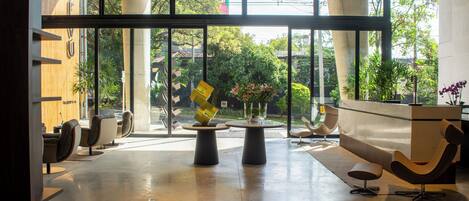 A spacious lobby with a reception desk, seating area, and large windows offering a view of the outdoors.