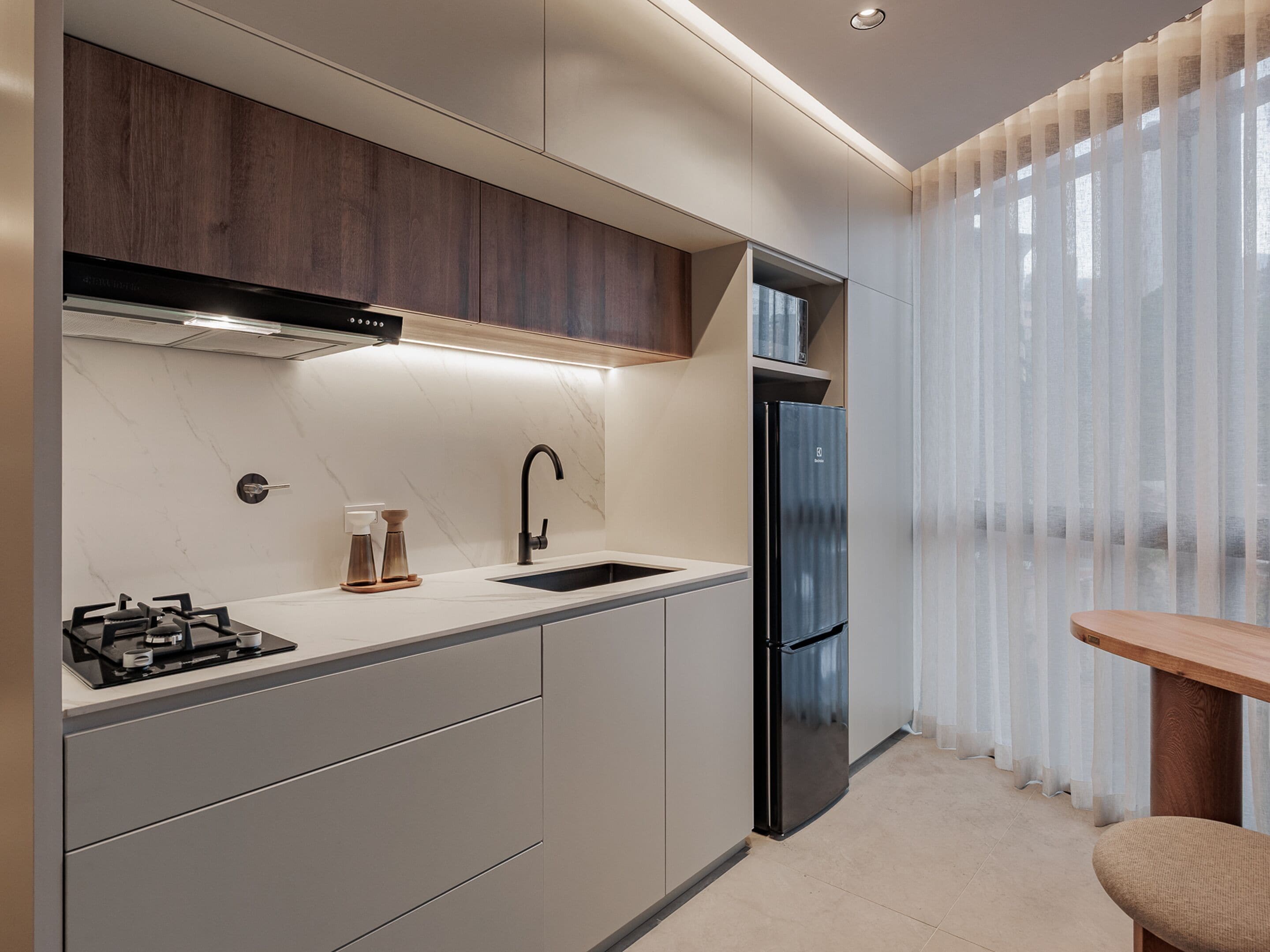 Eine moderne Küche mit eingebautem Gasherd, einem Edelstahl-Kühlschrank und einem Holzschrank über der Spüle.