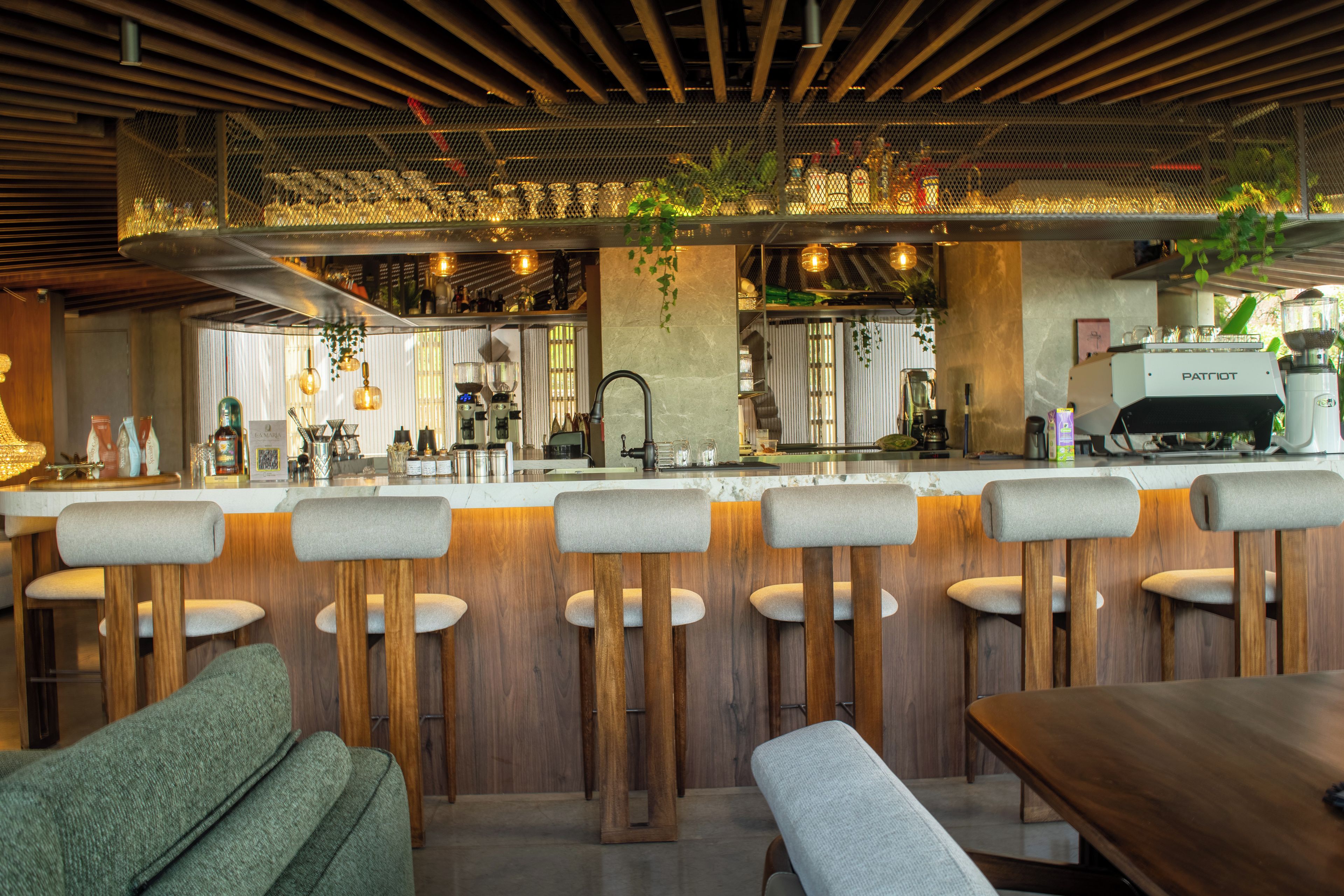 A bar area with wooden stools, a bar counter, and a coffee machine.