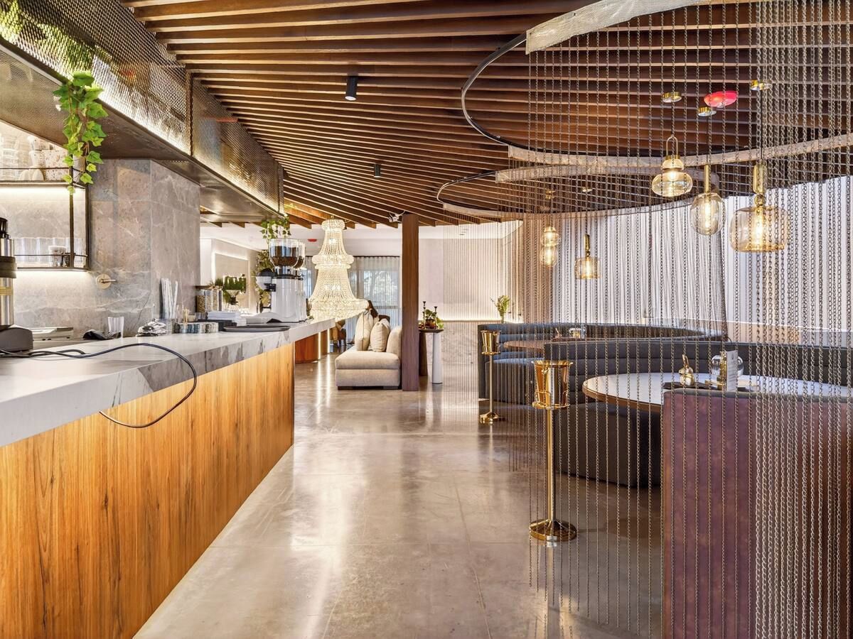 A modern interior with a wooden reception desk, seating area, and hanging pendant lights.