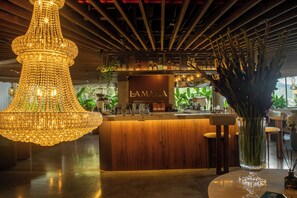 A bar area with a wooden counter, a hanging crystal chandelier, and a sign that reads 'LAMIA'.