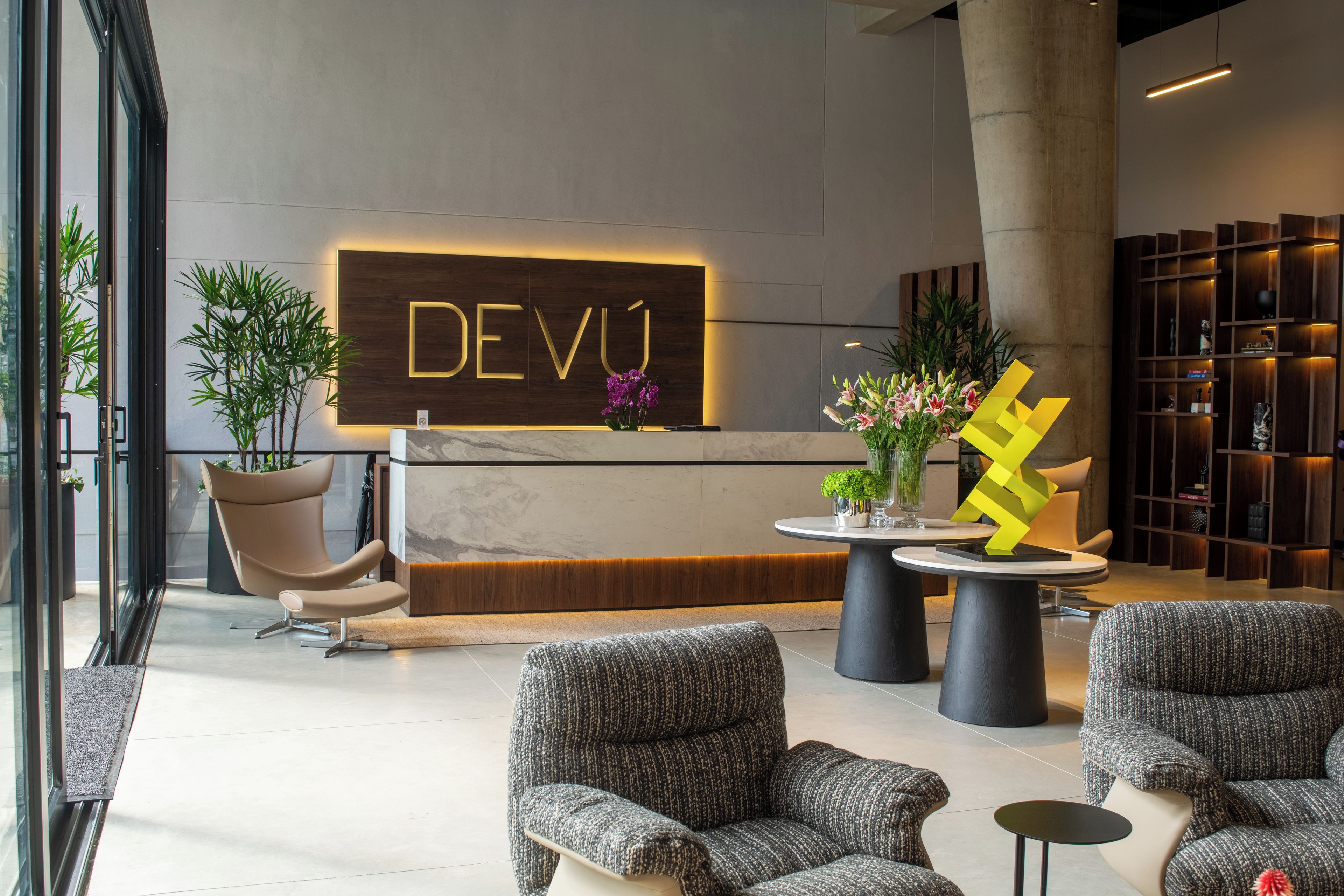 Un'area reception dal design moderno, con scrivania, sedute e una scultura decorativa.