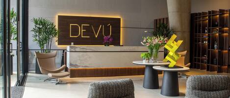 Un área de recepción de diseño moderno, con mostrador de recepción, asientos y una escultura decorativa.
