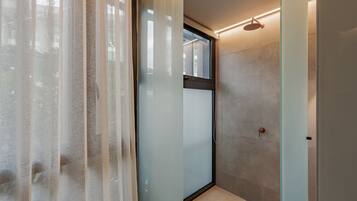 A modern bathroom with a glass shower enclosure, frosted glass doors, and a visible window.